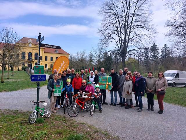 Eine Gruppe von Menschen vor dem kaiserlichen Schloss Eckartsau, der Geschäftsführer von Weinviertel, Hr. Steinacker, hält einen grossen Radroutenwegweiser in der Hand.